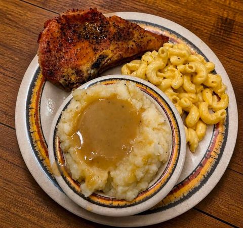 Baked pork chop with macaroni and cheese and mashed potatoes with gravy on a plate
